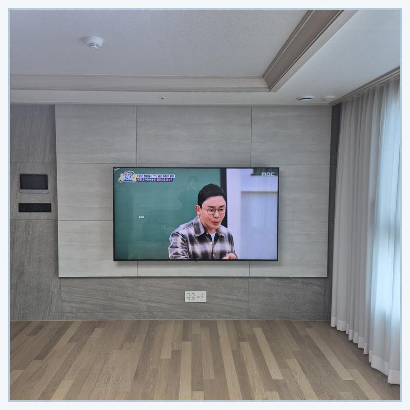 측면 여백과 콘센트 접근성을 검토하는 TV 설치 사진 · 오정 브라켓 확인